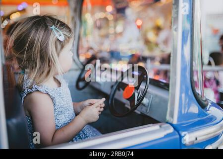 Petite fille chevauchant carrousel à un parc d'expositions Banque D'Images