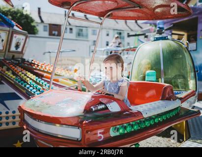 Petite fille chevauchant carrousel à un parc d'expositions Banque D'Images