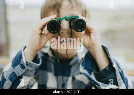 Boy looking through binoculars Banque D'Images