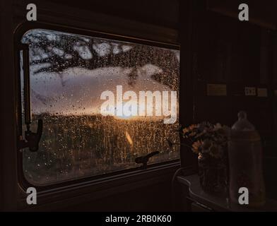 Vue du coucher de soleil à travers la fenêtre pluvieuse du camping-car Banque D'Images