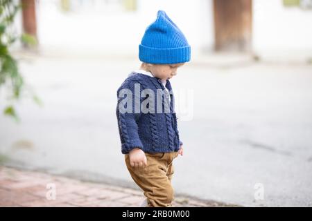 Petit garçon avec pantalon en cuir, cardigan et bonnet en laine Banque D'Images