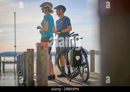 Couple, homme et femme voyageant avec des vélos, vélo de trekking, reposant sur la jetée Banque D'Images