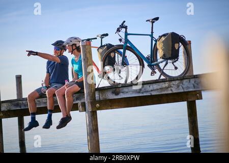 Couple, homme et femme voyageant avec des vélos, vélo de trekking, reposant sur la jetée Banque D'Images