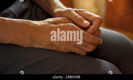 Les mains du vieil homme sont à genoux, attendant. Banque D'Images