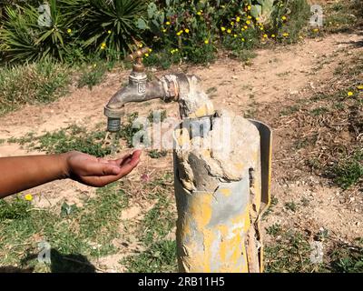 L'eau coule d'un robinet dans la main d'un enfant Banque D'Images