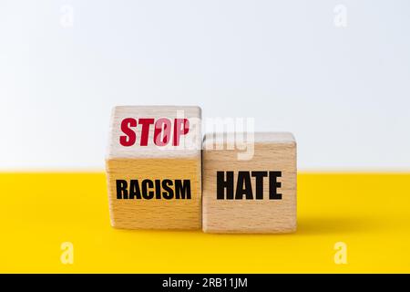 Blocs de bois qui changent la phrase racisme haine dans le slogan Stop haine, beau fond jaune et blanc Banque D'Images