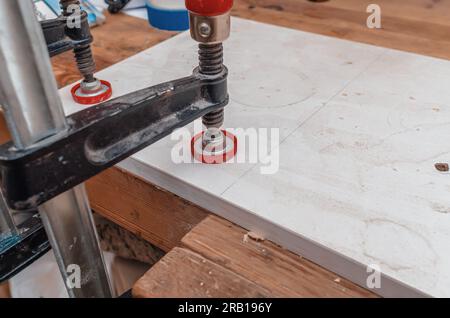 La pince du menuisier maintient la planche de bois à la table. Fond de menuiserie industrielle. Banque D'Images