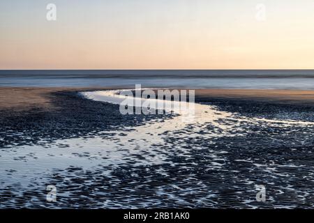 Vue sur St. Peter Ording plage au coucher du soleil avec un tideway à marée basse Banque D'Images