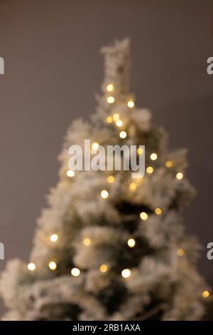Silhouette de sapin de Noël flou avec des points lumineux de la chaîne de lumières de fée Banque D'Images