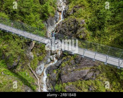 Italie, Trentin, province de trente, cycliste avec e-vtt sur le pont tibétain suspendu au-dessus du Rio de la Vecia le long de la piste cyclable Primiero San Martino di Castrozza, Dolomites Banque D'Images