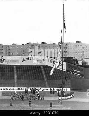 New York, New York : 1929. Le maire Jimmy Walker hisse le drapeau du Championnat du monde de baseball pour le premier match à domicile de la saison au Yankee Stadium de New York. Notez la batte baseballl au-dessus du poteau de drapeau comme une girouette. Banque D'Images