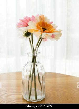La fleur artificielle dans le vase en verre clair sur la table en bois près de la fenêtre pour décoré dans le café, vue de face avec l'espace de copie. Banque D'Images