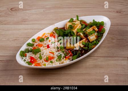 riz piment paneer dans une assiette blanche sur fond en bois Banque D'Images