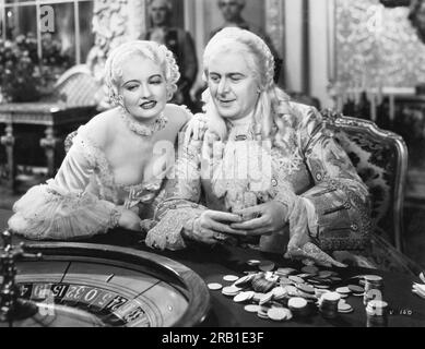 Hollywood, Californie : 1933 Une scène du film 'Voltaire', avec Doris Kenyon dans le rôle de Mme. Pompadour et Reginald Owen en tant que roi Louis XV comme il joue à une roulette. Banque D'Images