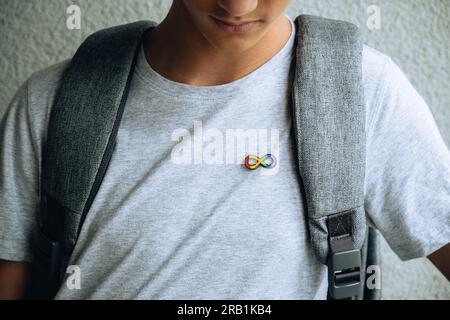 Adolescent avec autisme infini symbole arc-en-ciel signe métallique broche broche broche broche broche sur t-shirt. Journée mondiale de sensibilisation à l'autisme, mouvement des droits à l'autisme Banque D'Images