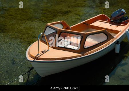 Petit vieux bateau à moteur amarré dans l'eau claire pour le concept de loisirs d'été Banque D'Images