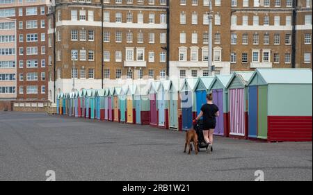 Personnes non reconnues marchant et faisant de l'exercice sur le chemin côtier près des cabanes de plage dans Brighton sussex Royaume-Uni Banque D'Images