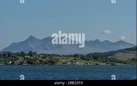 Île de Skye, Écosse, Royaume-Uni. 6 juin 2023. Vue panoramique sur les montagnes de Cuillin à travers la campagne verdoyante et les maisons résidentielles sur l'île de Skye. Banque D'Images