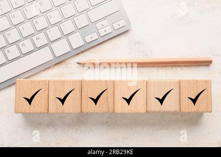 Cubes en bois avec des coches, crayon et clavier d'ordinateur sur fond clair Banque D'Images