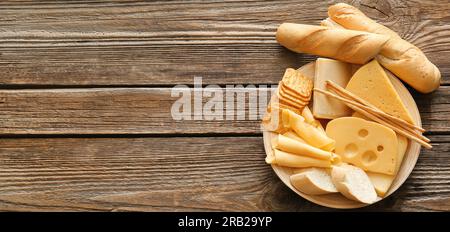 Assiette avec différentes sortes de fromage, pain et collations sur fond en bois avec espace pour le texte Banque D'Images