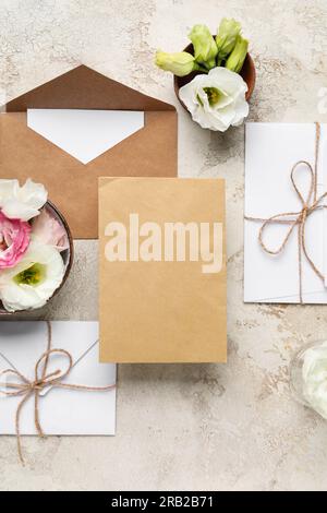 Composition avec enveloppes, cartes vierges et fleurs d'eustoma sur fond beige. Concept d'invitation de mariage Banque D'Images