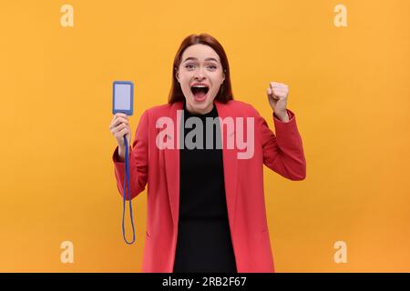 Femme émotionnelle avec badge vip Pass sur fond orange Banque D'Images