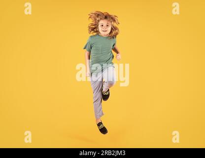 Un garçon dynamique sautant et levant les mains sur un arrière-plan de studio isolé. Photo de taille de corps pleine longueur de saut haut enfant garçon, en hurlant vers le haut runni Banque D'Images