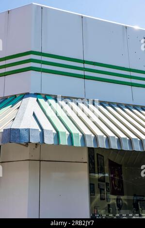 L'architecture verte et blanche sur le bâtiment rétro vintage montre un auvent neuf ou rénové au coin avec fenêtre. C'est peut-être une vieille entreprise de station-service. Banque D'Images