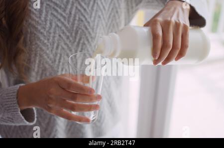 Jeune femme versant du lait dans le verre. Banque D'Images