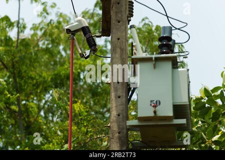 électricien à l'aide d'une pince pour réparer la coupure du fusible sur le poteau électrique haute tension soutenu par un isolant. Banque D'Images