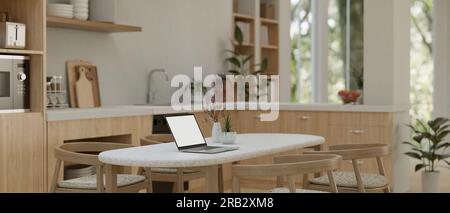 Un ordinateur portable avec une maquette d'écran blanc est sur une table à manger minimale dans un beau style de cuisine scandinave. rendu 3d, illustration 3d. Banque D'Images