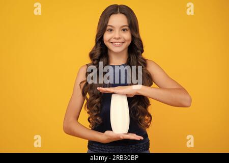 Enfant avec après shampooing. Soins cosmétiques quotidiens. L'adolescent de 12, 13, 14 ans tient une bouteille de soins pour les cheveux et la peau. Beauté santé et cosmétiques. Banque D'Images