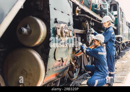 Équipe de mécanicien de train travaillant entretien entretien vieux sale vieux moteur à vapeur classique dans l'atelier de réparation de train à la gare. Banque D'Images