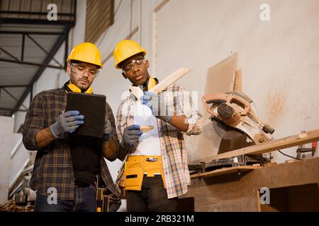 Équipe de travailleurs travaillant ensemble avec parler du travail en bois de conception, travailleur du personnel moderne d'usine de meubles en bois. Banque D'Images