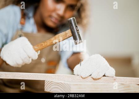 gros plan charpentier de travailleur du bois utilisez l'outil de marteau avec des clous pour les meubles en bois faits à la main dans l'atelier. Banque D'Images