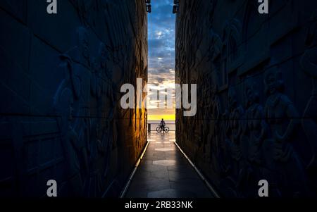 Silhouette d'un homme avec un vélo au bout du tunnel de la tour Nghinh Phong dans la province de Phu yen, Vietnam, surplombant la mer à l'aube Banque D'Images