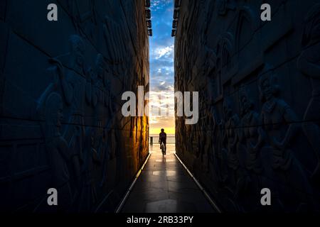 Silhouette d'un homme avec un vélo au bout du tunnel de la tour Nghinh Phong dans la province de Phu yen, Vietnam, surplombant la mer à l'aube Banque D'Images