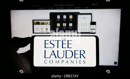 Personne détenant le smartphone avec le logo de la société américaine The Estee Lauder Companies Inc. Sur l'écran en face du site Web. Concentrez-vous sur l'affichage du téléphone. Banque D'Images