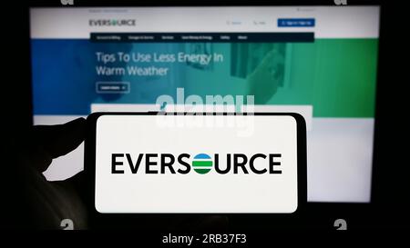 Personne tenant le téléphone portable avec le logo de la société de services publics américaine Eversource Energy sur l'écran en face de la page Web de l'entreprise. Concentrez-vous sur l'affichage du téléphone. Banque D'Images