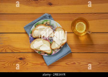 thé noir chaud et pain blanc avec beurre et fromage sur une vieille table Banque D'Images
