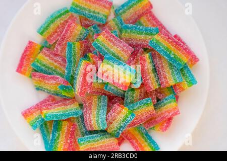 Marmelades arc-en-ciel dans une assiette blanche. vue d'en haut. Goodies et bonbons . Les joies des enfants. Assiettes à mâcher acides et sucrées avec du sucre. Couleur vive c Banque D'Images