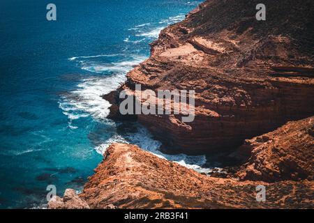 Photo aérienne du haut d'une falaise escarpée regardant vers le bas sur les vagues qui s'écrasent sur les rochers dans l'océan. Tourné en australie occidentale Kalbarri National Banque D'Images