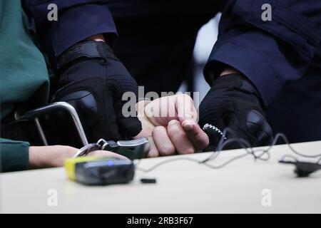 Itzehoe, Allemagne. 07 juillet 2023. Un fonctionnaire du tribunal ouvre les menottes de l'accusé Ibrahim A. dans la salle d'audience du China Logistic Center. Le procès d'Ibrahim A. pour l'attaque mortelle au couteau dans un train régional à Brokstedt, Schleswig-Holstein, le 25 janvier 2023, a débuté vendredi au tribunal régional d'Itzehoe. Crédit : Christian Charisius/dpa-POOL/dpa/Alamy Live News Banque D'Images