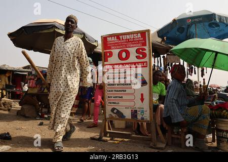 Un homme affiche de la nouvelle monnaie nigériane alors qu'il se tenait devant une banque avec des gens vus en file d'attente à Abuja Banque D'Images