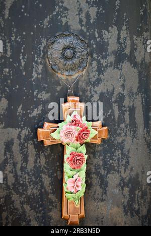 Petite croix en céramique avec des fleurs comme décoration dans un cimetière en France. Banque D'Images