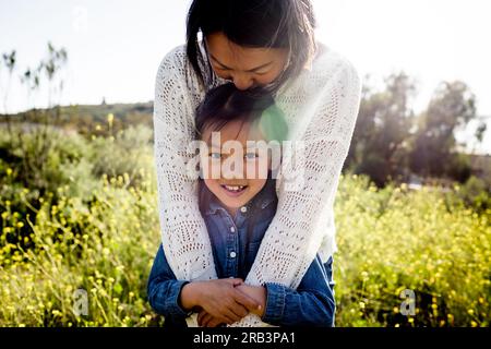 Maman asiatique Kissing tête de fille dans Wildflowers à San Diego Banque D'Images