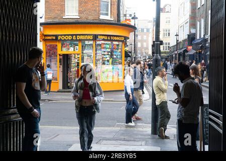 Météo britannique, 6 juillet 2023, Londres : après quelques jours plus froids que la moyenne, le temps chaud revient à Londres, amenant les foules à Soho. Sur Greeek Street, les fumeurs s'attardent tandis que les piétons se précipitent devant. Crédit : Anna Watson/Alamy Live News Banque D'Images