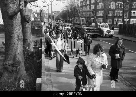 Des enfants curieux regardent le WPC Elaine Bishop, 21 ans, vêtu de vêtements similaires à ceux portés par l'assassinée Playboy Bunny Girl Eve Stratford, reconstituer sa dernière marche en retraçant les pas d'Eve de la station de métro locale à l'appartement de Lyndhurst Drive, dans l'est de Londres. VEUILLEZ NOTER QUE CE N'EST PAS UNE IMAGE D'EVE STRATFORD Banque D'Images