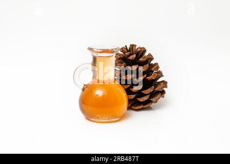 bouteille de sirop ou de miel à côté d'une pomme de pin monterey, isolé sur fond blanc, doux foyer en gros plan Banque D'Images