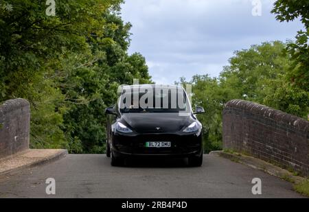 Milton Keynes, Royaume-Uni - 6 juillet 2023 : 2022 TESLA MODÈLE y voiture électrique à LONGUE PORTÉE AWD sur un pont étroit, bosse arrière Banque D'Images